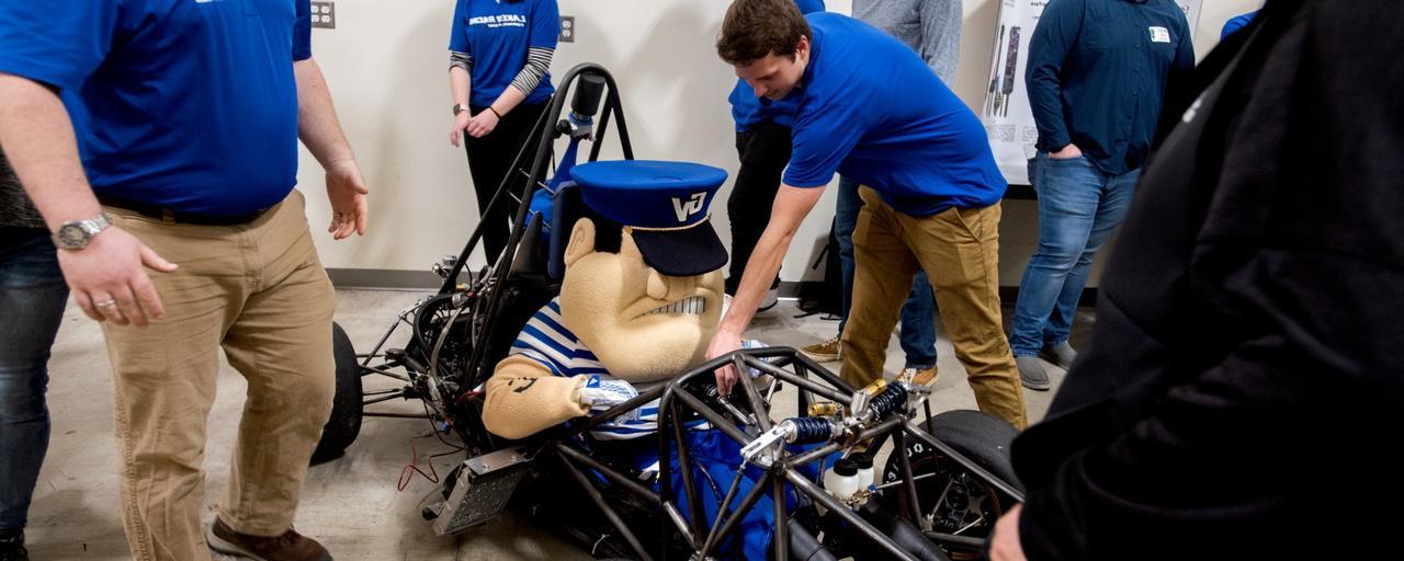 A race car with men in it and standing around it